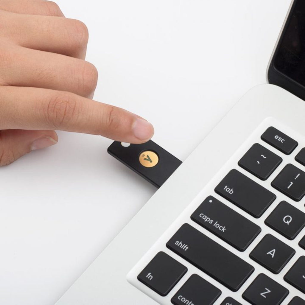 Hand steckt den YubiKey 5 NFC in den seitlichen USB-A-Anschluss eines Notebooks