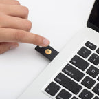 Hand steckt den YubiKey 5 NFC in den seitlichen USB-A-Anschluss eines Notebooks