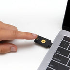 Hand steckt den YubiKey 5C NFC in den seitlichen USB-C-Anschluss eines Notebooks